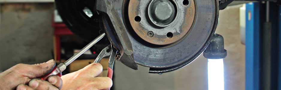 A close up photograph of a mechanic fixing a cars brake pad disk