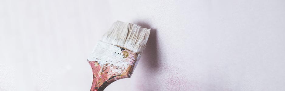 An example of a paintbrush being used by a decorator to paint a white wall